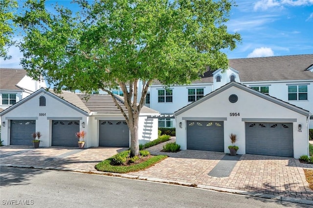 view of front facade featuring stucco siding, a garage, driveway, and a tiled roof