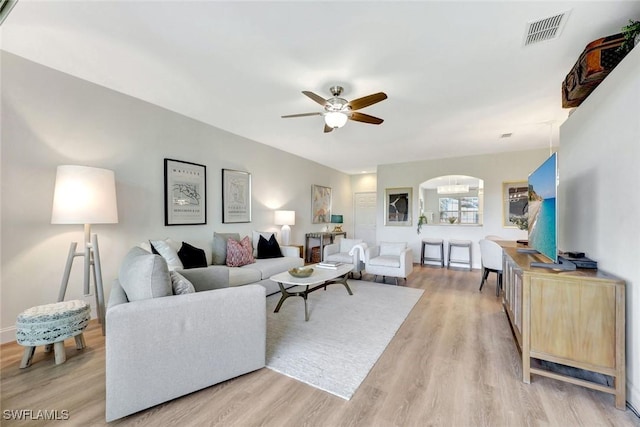 living room featuring a ceiling fan, visible vents, and light wood finished floors