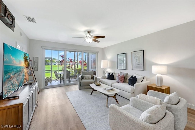 living area featuring visible vents, baseboards, a ceiling fan, and light wood finished floors