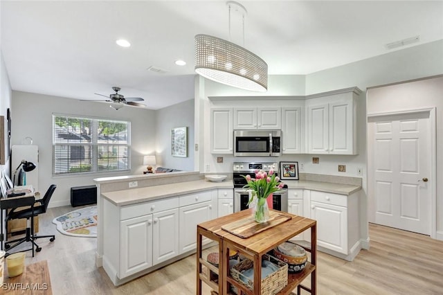 kitchen with visible vents, a peninsula, ceiling fan, light countertops, and appliances with stainless steel finishes