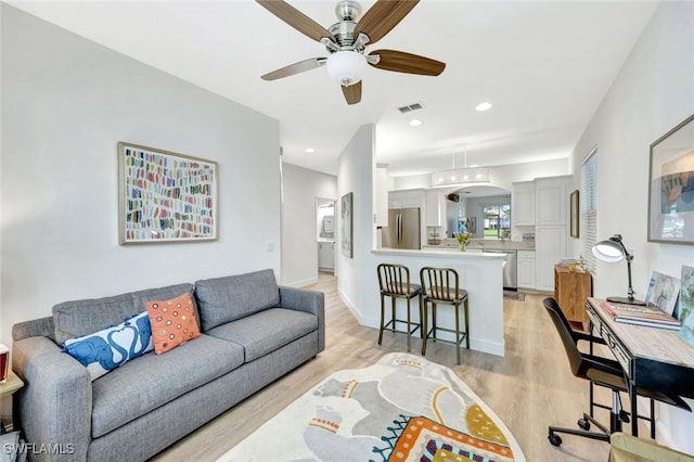 living area with recessed lighting, visible vents, a ceiling fan, and light wood finished floors