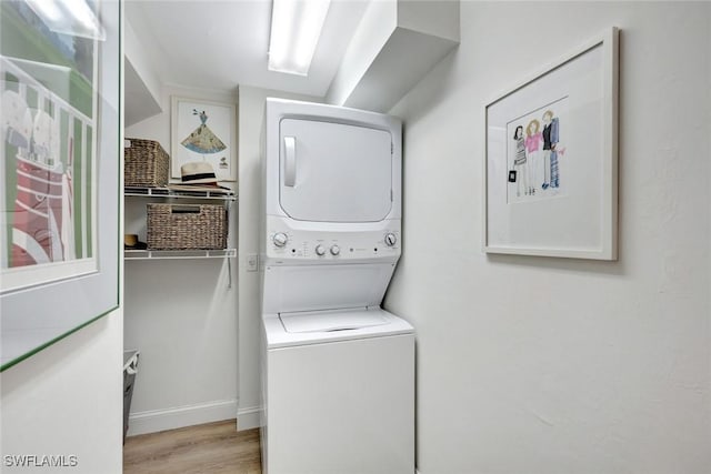 laundry room featuring laundry area, wood finished floors, and stacked washer and clothes dryer