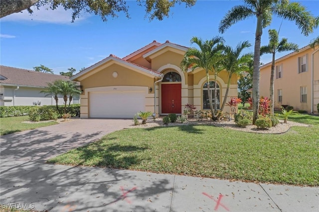 mediterranean / spanish home with stucco siding, an attached garage, decorative driveway, and a front yard