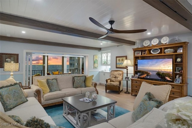 living room with ceiling fan, beam ceiling, and wood finished floors