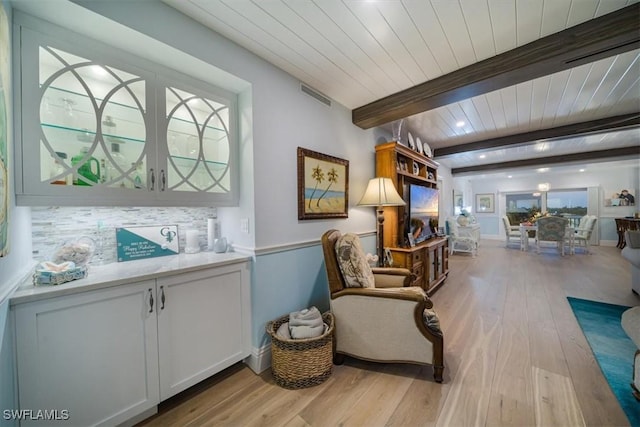 sitting room featuring visible vents, light wood-style flooring, wood ceiling, and beamed ceiling