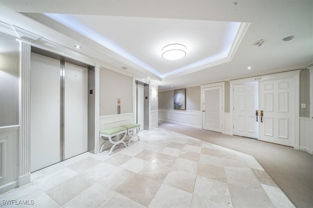 below grade area with a wainscoted wall, elevator, ornamental molding, and a decorative wall