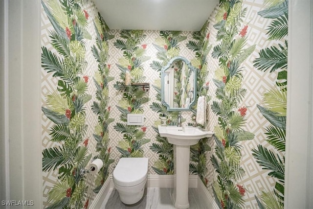 half bathroom with toilet, wallpapered walls, and baseboards