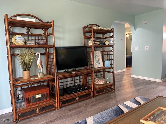 living area with wood finished floors, arched walkways, and baseboards