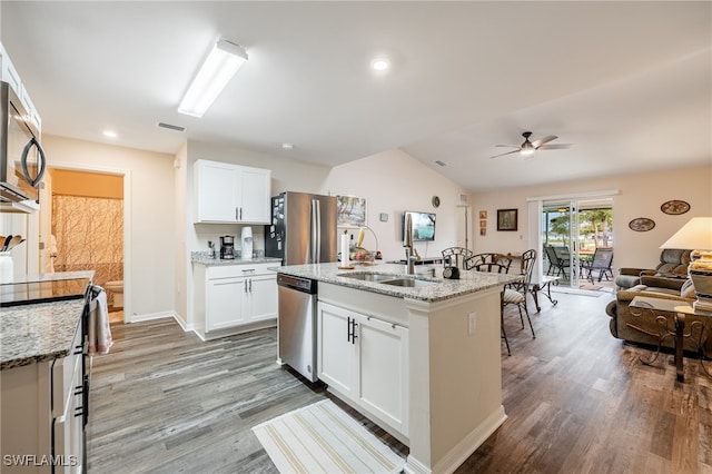 kitchen featuring light stone counters, open floor plan, stainless steel appliances, and a sink