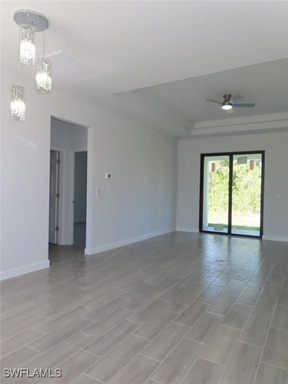 empty room featuring a tray ceiling and baseboards