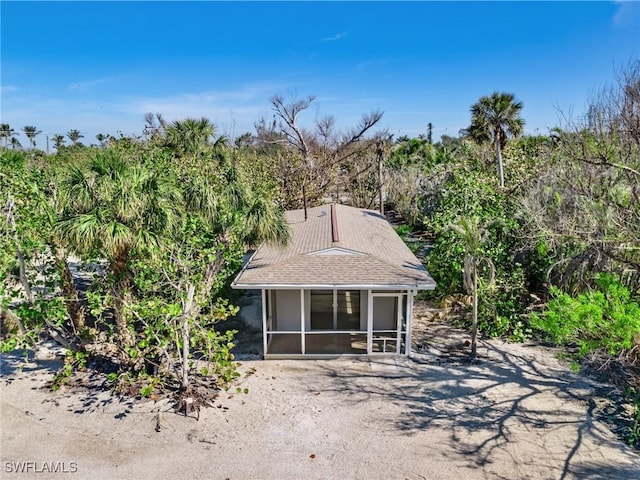 view of front of home featuring roof with shingles and a sunroom