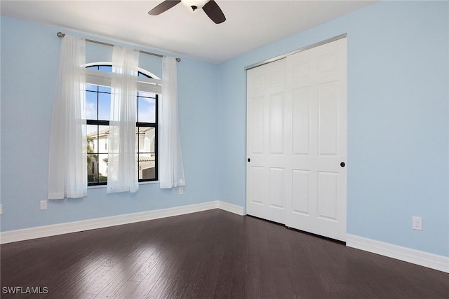 unfurnished bedroom featuring a ceiling fan, baseboards, dark wood-style flooring, and a closet