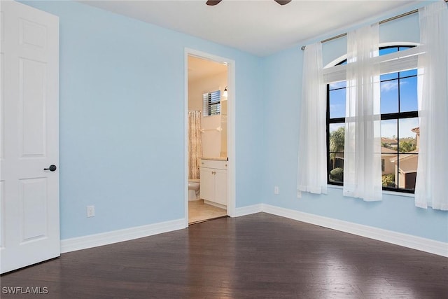 unfurnished bedroom featuring connected bathroom, baseboards, and wood finished floors