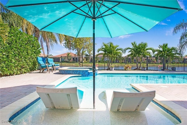 view of swimming pool featuring a patio area, a pool with connected hot tub, and fence