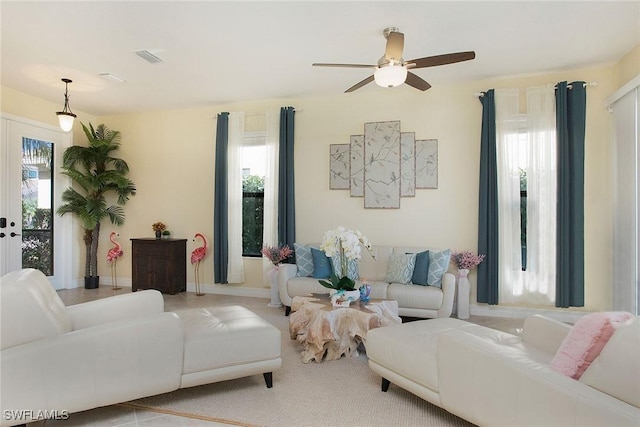 living area featuring a wealth of natural light, visible vents, french doors, and a ceiling fan