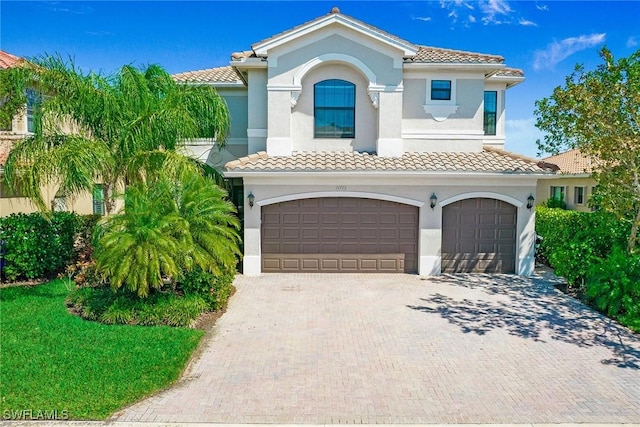 mediterranean / spanish house with a tile roof, decorative driveway, and stucco siding