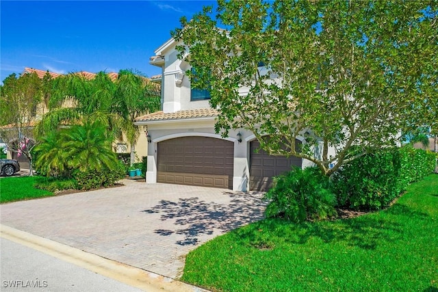 view of front of property with stucco siding, an attached garage, a tile roof, and decorative driveway