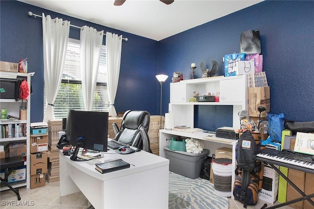 tiled office featuring a ceiling fan and a textured wall