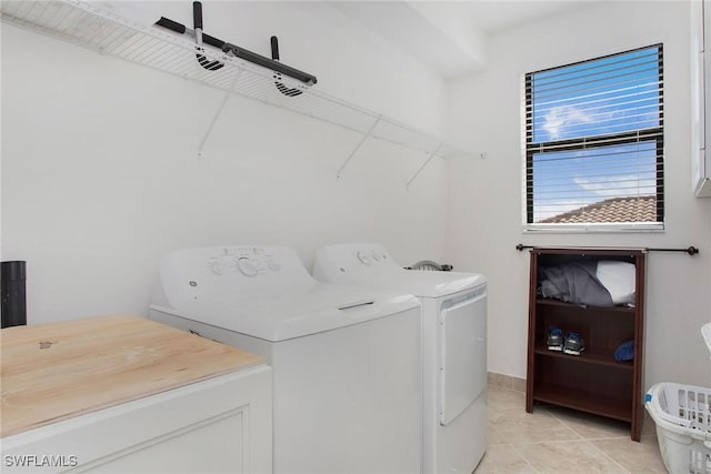 clothes washing area featuring light tile patterned floors, cabinet space, and separate washer and dryer