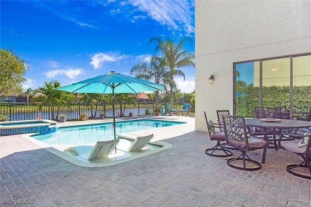 view of pool with outdoor dining area, a patio area, fence, and a pool with connected hot tub