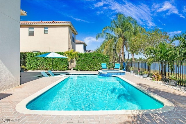 view of swimming pool with a patio area, a pool with connected hot tub, and fence