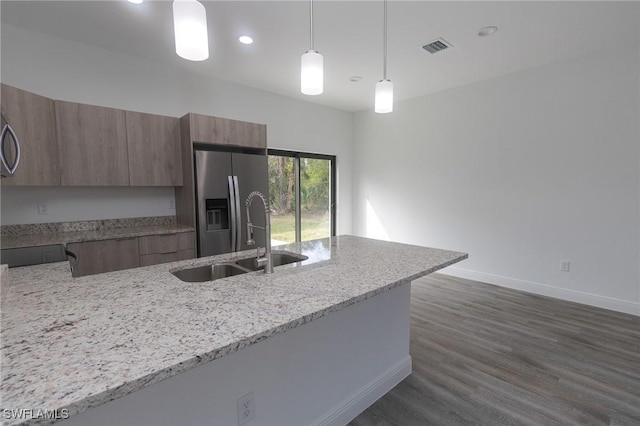 kitchen with visible vents, light stone countertops, stainless steel refrigerator with ice dispenser, modern cabinets, and a sink