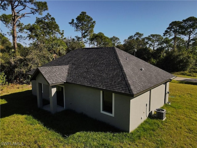 view of property exterior with a yard, roof with shingles, cooling unit, and stucco siding