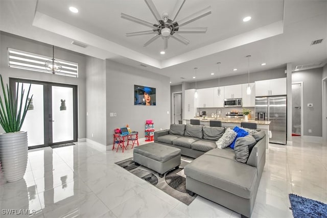 living area featuring visible vents, a raised ceiling, and french doors