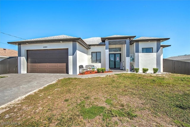 prairie-style home with stucco siding, driveway, fence, a front yard, and an attached garage