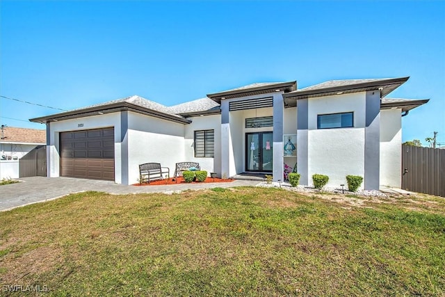 prairie-style home featuring stucco siding, decorative driveway, an attached garage, and fence