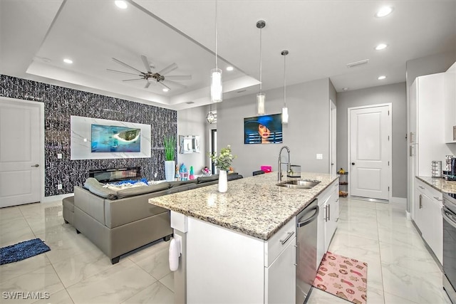 kitchen featuring a tray ceiling, recessed lighting, a sink, an accent wall, and marble finish floor