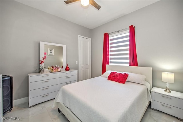 bedroom with a ceiling fan, marble finish floor, a closet, and baseboards