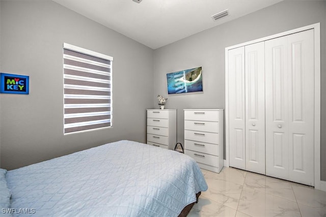 bedroom with visible vents, marble finish floor, and a closet