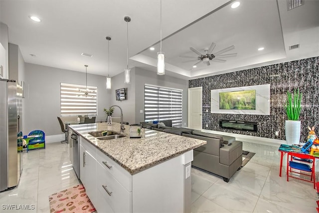 kitchen with open floor plan, stainless steel appliances, a tray ceiling, and a sink