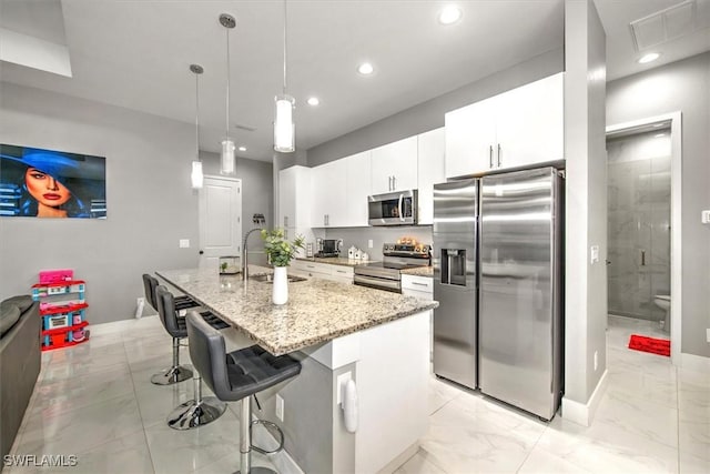 kitchen with visible vents, an island with sink, a sink, appliances with stainless steel finishes, and a breakfast bar area