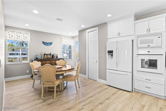 dining room featuring light wood-style flooring, plenty of natural light, and visible vents