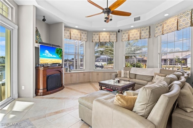 sunroom with a wealth of natural light, visible vents, a fireplace, and a tray ceiling