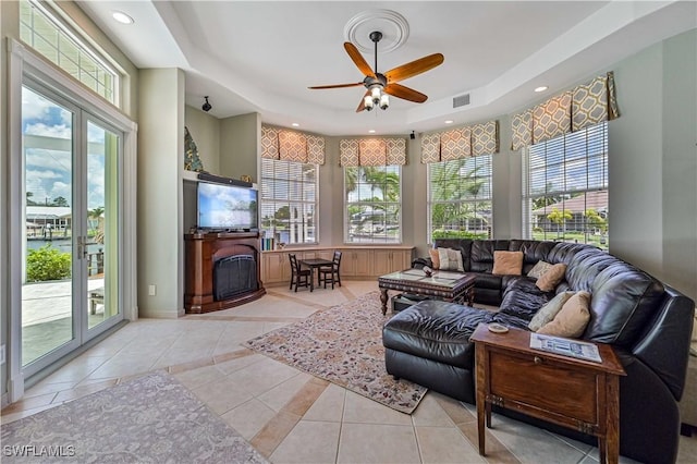 living room featuring tile patterned flooring, a fireplace, a wealth of natural light, and a tray ceiling