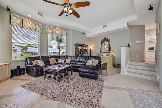 living area with visible vents, baseboards, stairs, and ceiling fan