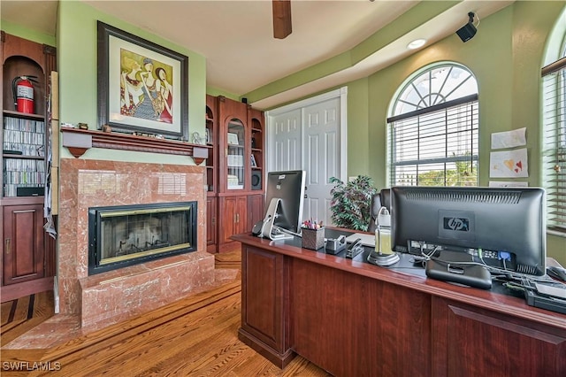 home office featuring wood finished floors, a high end fireplace, and ceiling fan