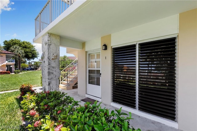 view of exterior entry with stucco siding and a yard