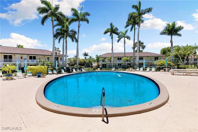 community pool with a residential view, a patio, and fence