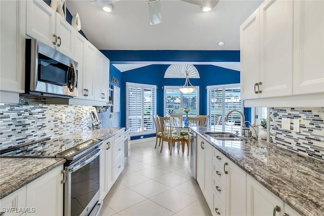 kitchen featuring light tile patterned floors, lofted ceiling, a sink, appliances with stainless steel finishes, and white cabinetry