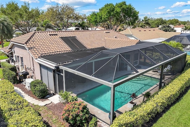 rear view of house with an outdoor pool, a patio area, glass enclosure, and a tiled roof