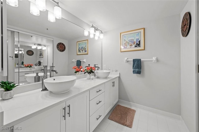 full bath with double vanity, baseboards, and a sink