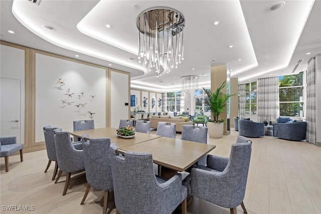 dining area featuring a wall of windows, light wood-style flooring, recessed lighting, a raised ceiling, and a chandelier