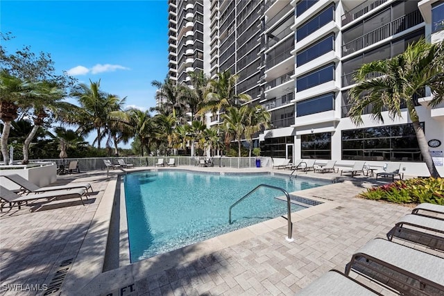 community pool with a patio area and fence