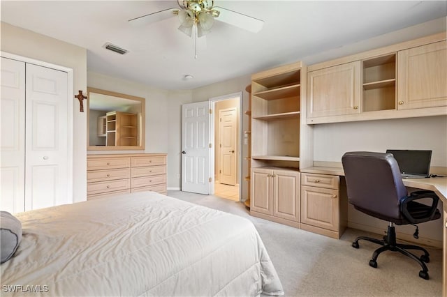 bedroom with a ceiling fan, visible vents, built in study area, a closet, and light carpet