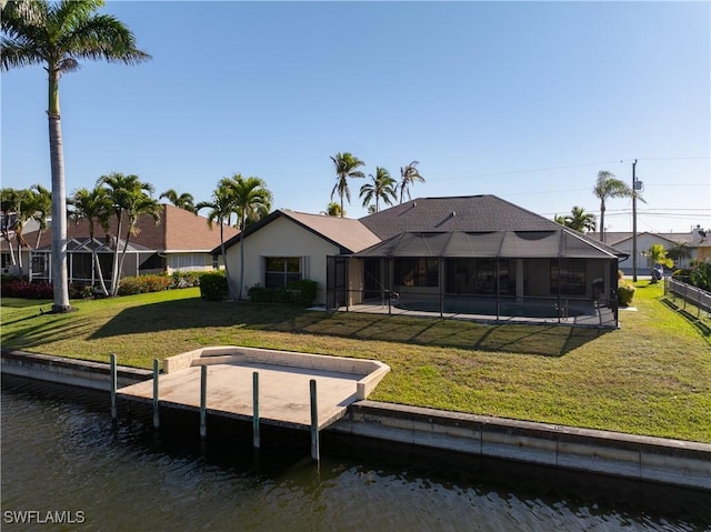 rear view of house featuring stucco siding, glass enclosure, a yard, and a water view