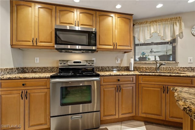 kitchen featuring a sink, light stone counters, and appliances with stainless steel finishes